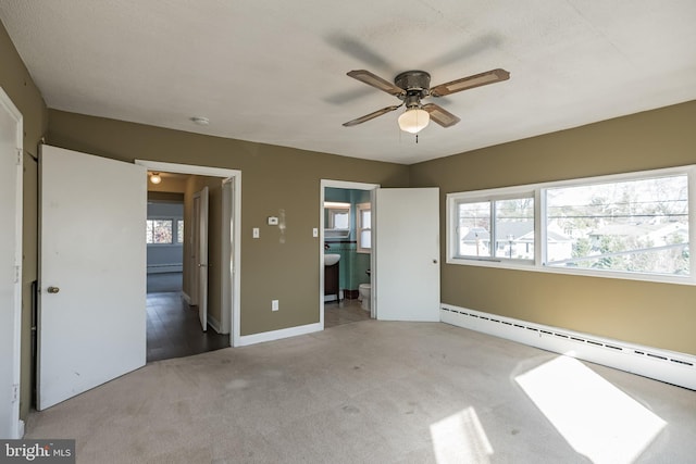 unfurnished bedroom featuring connected bathroom, light carpet, ceiling fan, and a baseboard heating unit