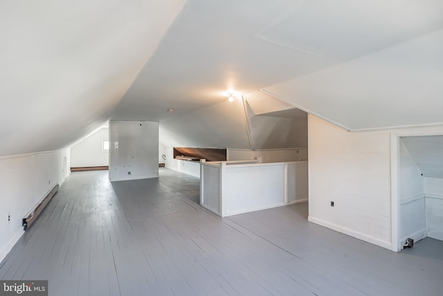 bonus room with wood-type flooring, lofted ceiling, and a baseboard heating unit