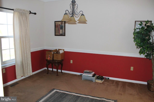 carpeted spare room featuring an inviting chandelier