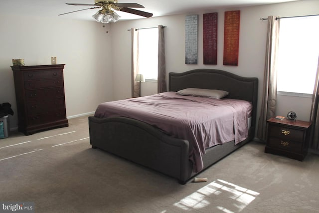 bedroom featuring light carpet, multiple windows, and ceiling fan