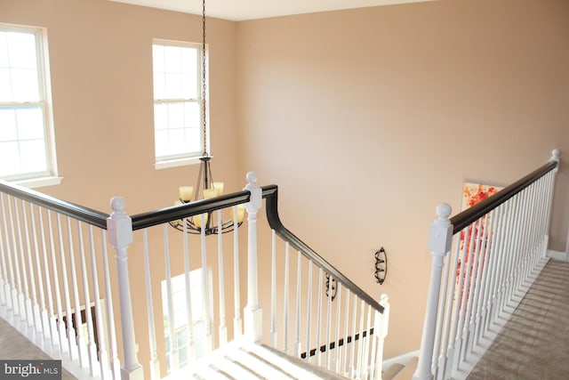 stairway with plenty of natural light, carpet floors, and an inviting chandelier