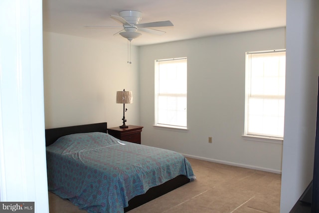 bedroom with multiple windows, ceiling fan, and light carpet