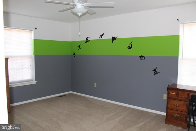 carpeted spare room featuring ceiling fan and a healthy amount of sunlight