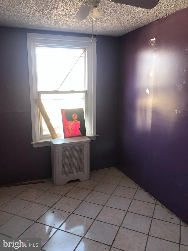 unfurnished room featuring a textured ceiling, ceiling fan, and light tile patterned floors