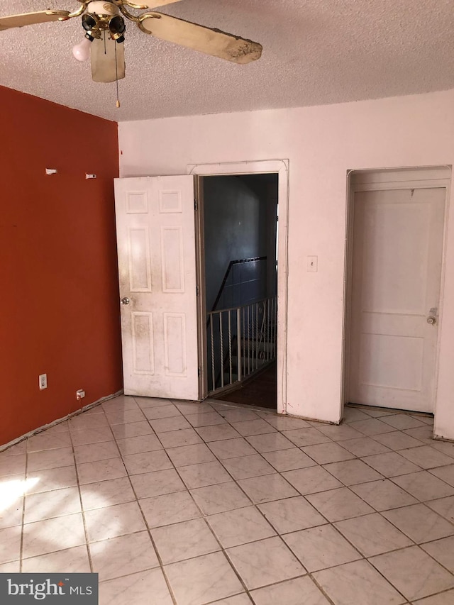 unfurnished bedroom featuring light tile patterned flooring, ceiling fan, and a textured ceiling