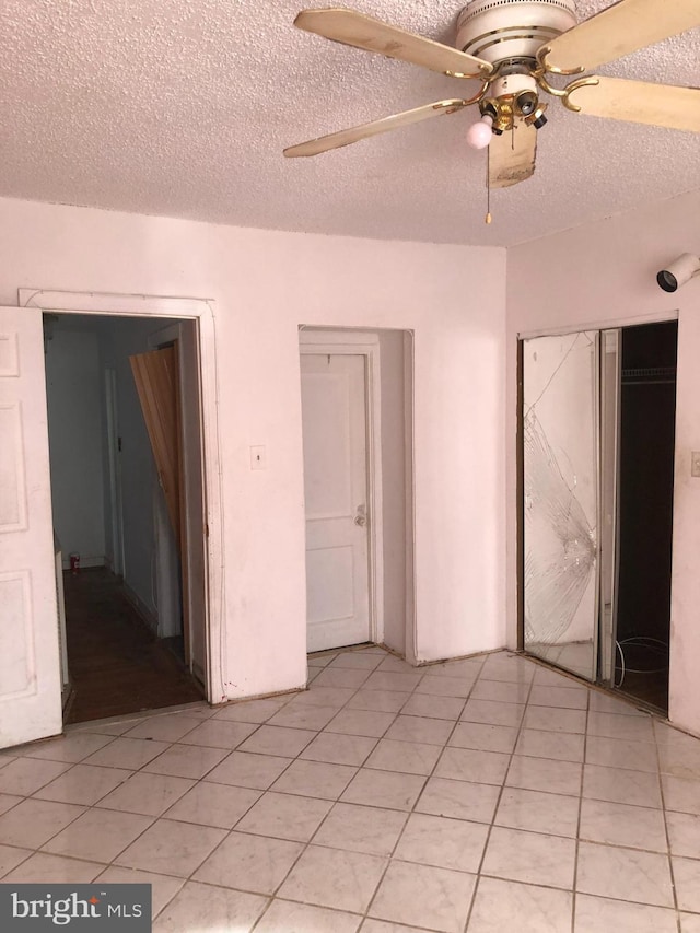 interior space with light tile patterned flooring, a textured ceiling, and ceiling fan