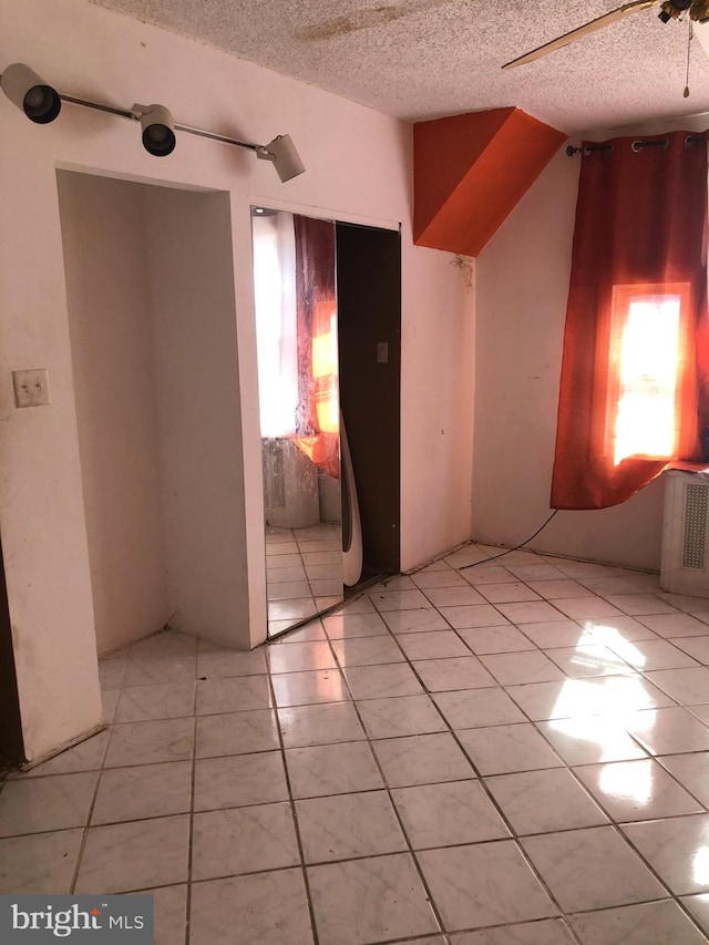 tiled empty room featuring a textured ceiling and ceiling fan