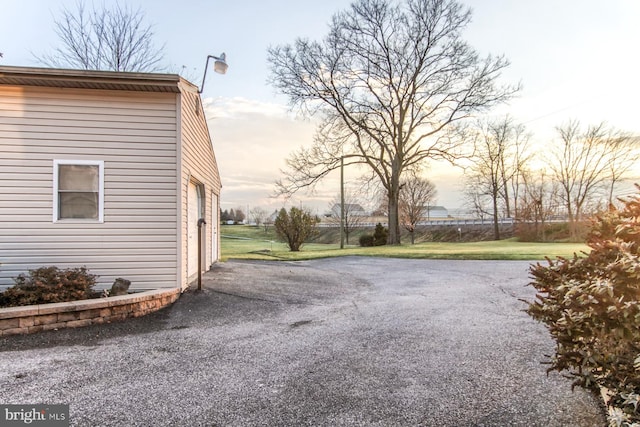 property exterior at dusk featuring a lawn and a garage