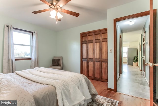 bedroom with ceiling fan, a closet, multiple windows, and light hardwood / wood-style flooring