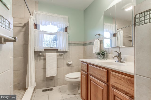 bathroom with vanity, tile patterned floors, toilet, tile walls, and curtained shower