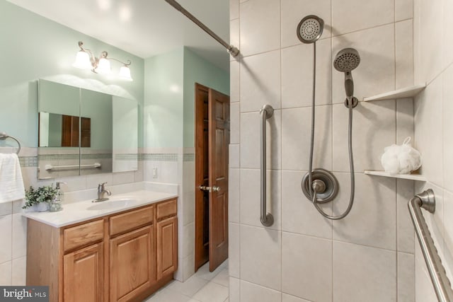 bathroom featuring tiled shower, vanity, and tile patterned flooring