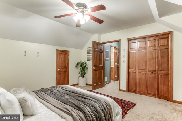 bedroom featuring ceiling fan, a closet, light carpet, and vaulted ceiling