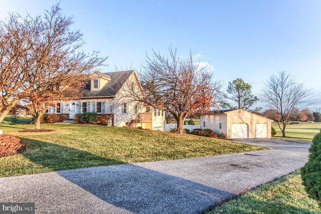 view of front facade featuring a garage, an outbuilding, and a front lawn