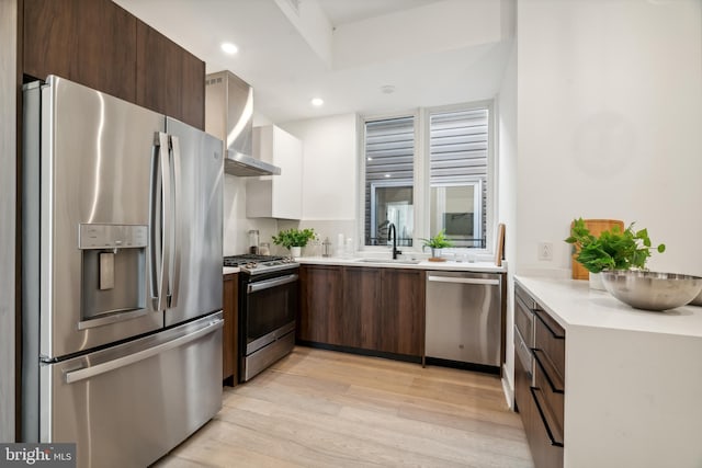1513 Christian St Unit 5, Philadelphia, PA 19146 - kitchen featuring appliances with stainless steel finishes, wall chimney range hood, a sink, light wood finished floors, and light countertops