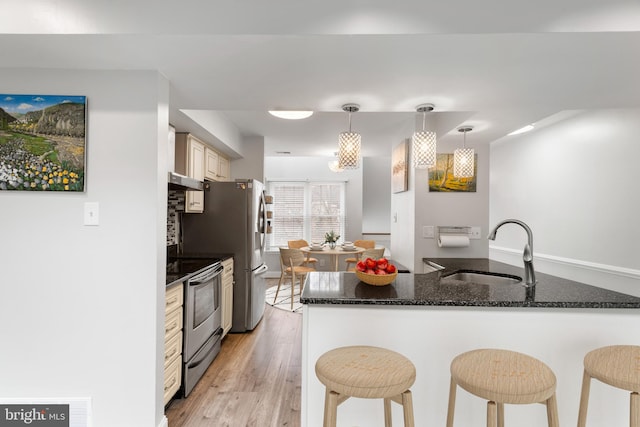 kitchen featuring kitchen peninsula, sink, pendant lighting, electric range, and light hardwood / wood-style flooring