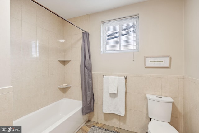 bathroom featuring shower / bath combo, tile walls, and toilet