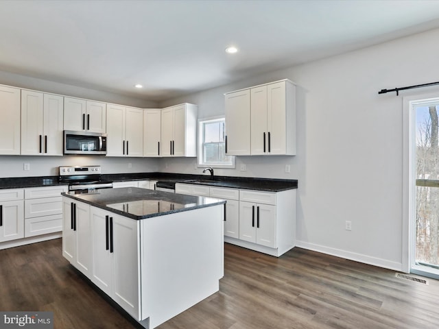 kitchen with sink, white cabinets, a kitchen island, and appliances with stainless steel finishes