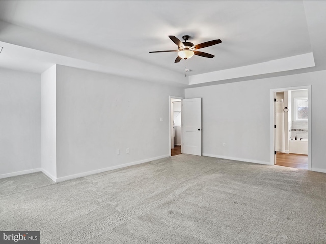 carpeted spare room featuring ceiling fan and a raised ceiling