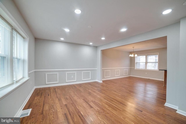 spare room with hardwood / wood-style floors and a chandelier