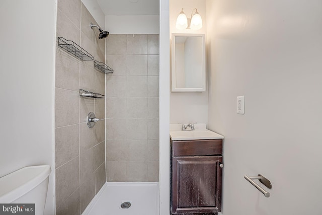 bathroom with vanity, toilet, and a tile shower