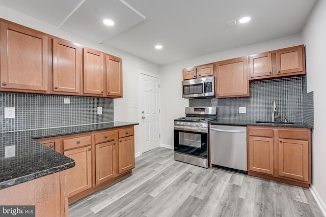 kitchen featuring decorative backsplash, sink, light wood-type flooring, and stainless steel appliances