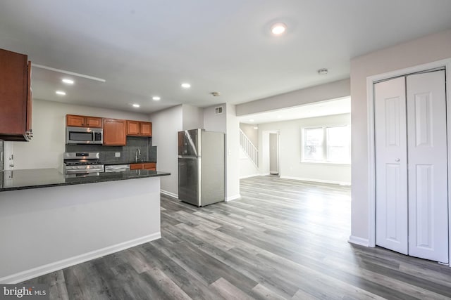 kitchen with hardwood / wood-style floors, kitchen peninsula, sink, and appliances with stainless steel finishes