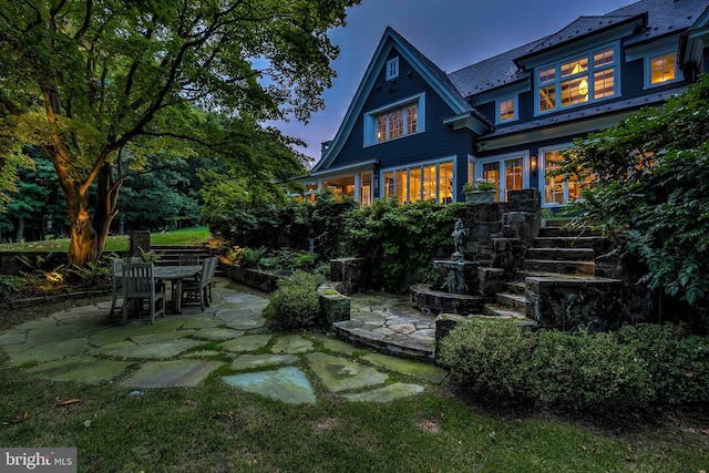 back house at dusk featuring a patio area