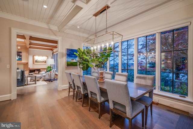 dining room featuring hardwood / wood-style flooring, ornamental molding, and beamed ceiling