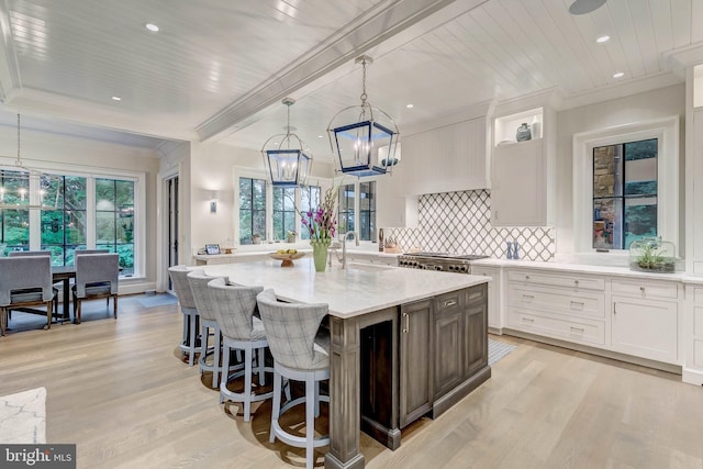 kitchen with sink, pendant lighting, light hardwood / wood-style flooring, white cabinets, and a large island