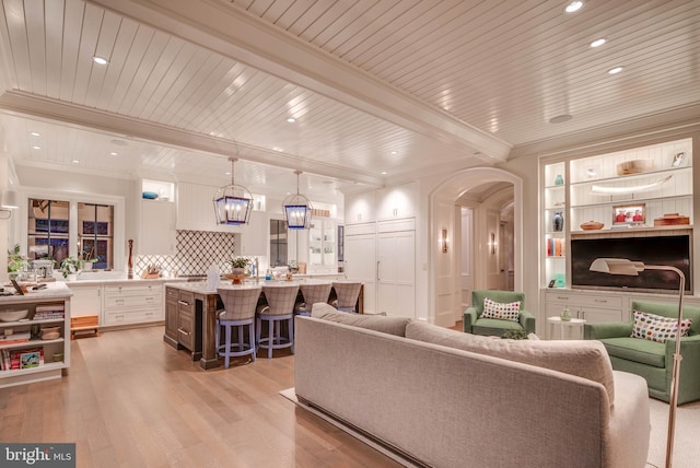 living room with beam ceiling, an inviting chandelier, light hardwood / wood-style flooring, crown molding, and wood ceiling