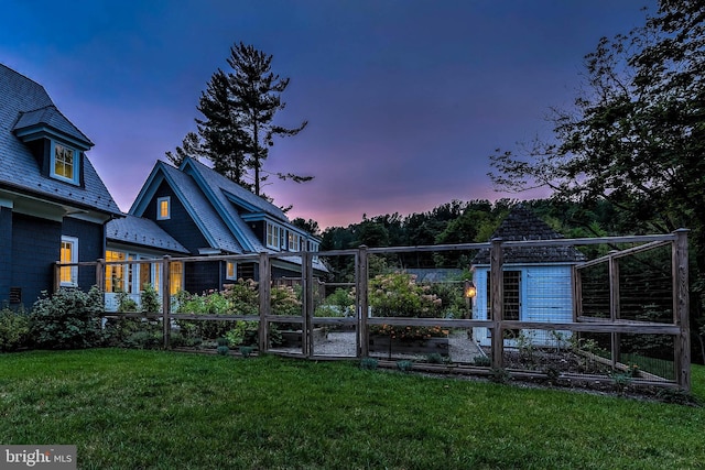 back house at dusk featuring a yard