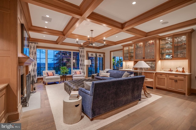 living room featuring coffered ceiling, crown molding, beam ceiling, light hardwood / wood-style flooring, and a chandelier