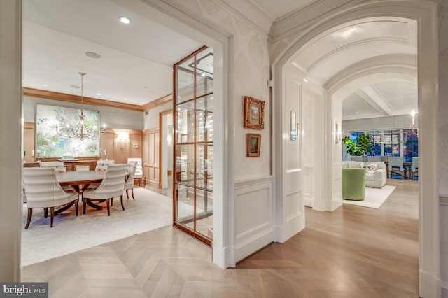 interior space with light parquet flooring, crown molding, and a chandelier