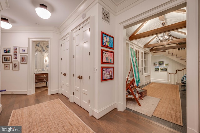 corridor featuring vaulted ceiling with beams, wood-type flooring, crown molding, and a chandelier