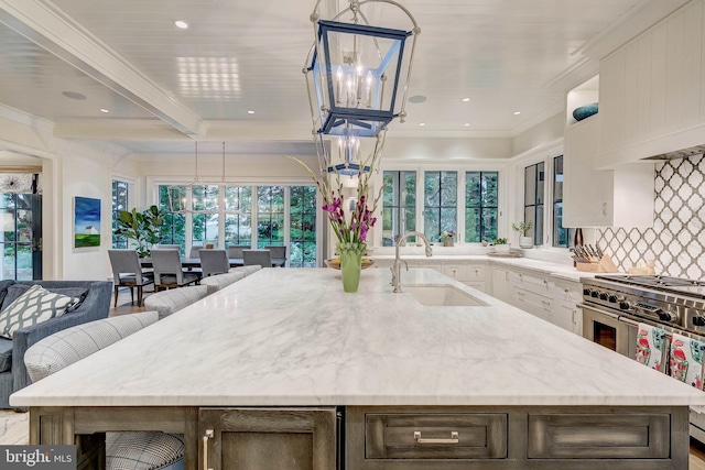 kitchen featuring white cabinets, decorative light fixtures, a healthy amount of sunlight, and sink