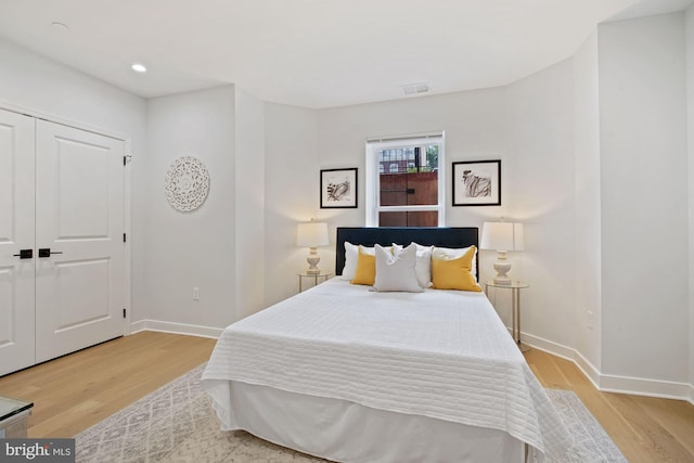 bedroom with light hardwood / wood-style floors and a closet