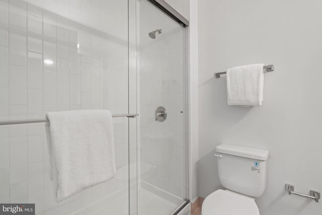 bathroom featuring toilet and a shower with shower door