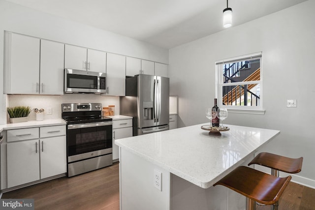 kitchen with decorative light fixtures, dark hardwood / wood-style floors, white cabinetry, and stainless steel appliances