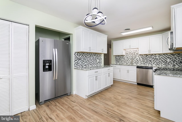 kitchen with light hardwood / wood-style floors, white cabinets, pendant lighting, and appliances with stainless steel finishes