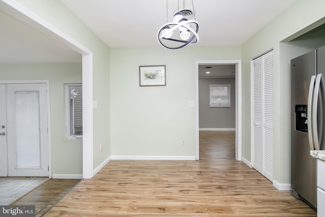 hallway with light hardwood / wood-style floors and an inviting chandelier