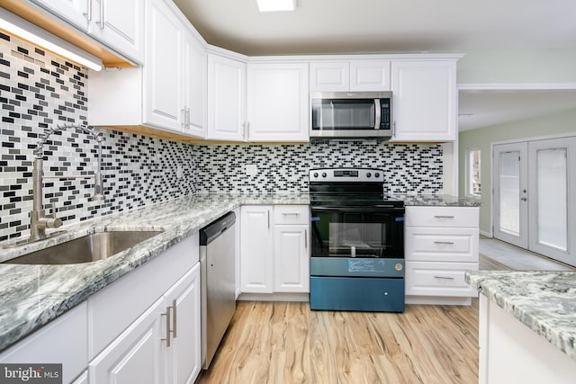 kitchen with white cabinetry, sink, stainless steel appliances, backsplash, and light hardwood / wood-style floors