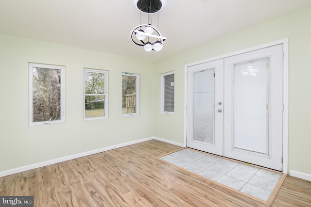 foyer with a chandelier, french doors, and light wood-type flooring