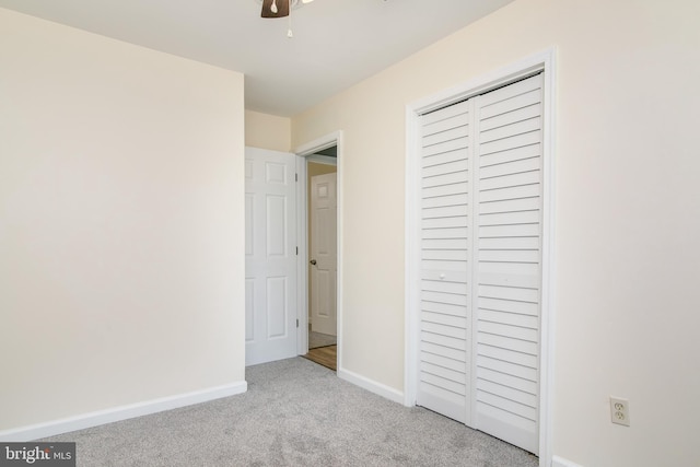 unfurnished bedroom with light carpet, a closet, and ceiling fan