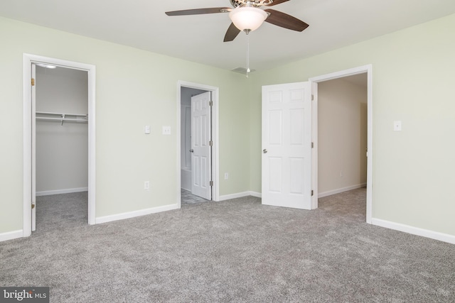 unfurnished bedroom with a spacious closet, a closet, ceiling fan, and light colored carpet