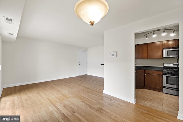 kitchen featuring rail lighting, stainless steel appliances, and light hardwood / wood-style floors