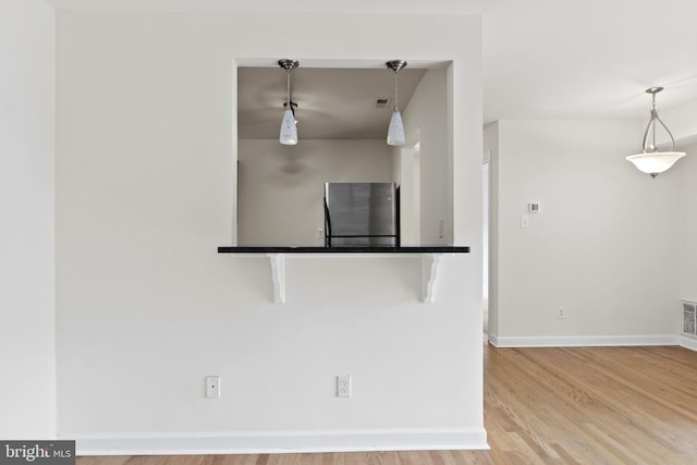 kitchen with light wood-type flooring, hanging light fixtures, and a breakfast bar area