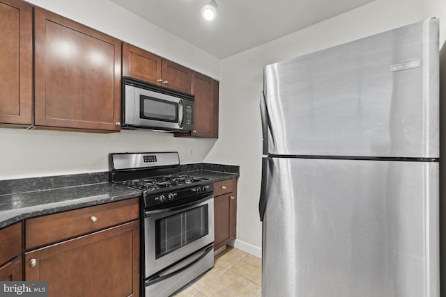 kitchen featuring light tile patterned flooring, dark stone counters, and appliances with stainless steel finishes