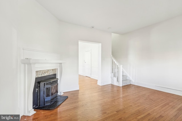 unfurnished living room with heating unit, a wood stove, and hardwood / wood-style flooring