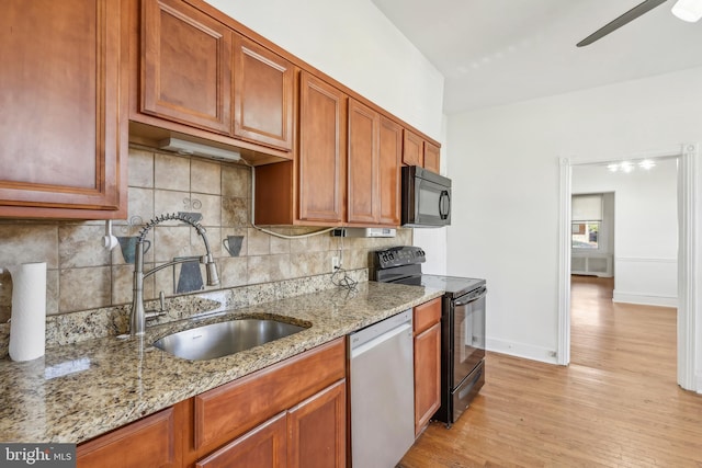 kitchen featuring stainless steel appliances, light hardwood / wood-style floors, sink, and light stone countertops