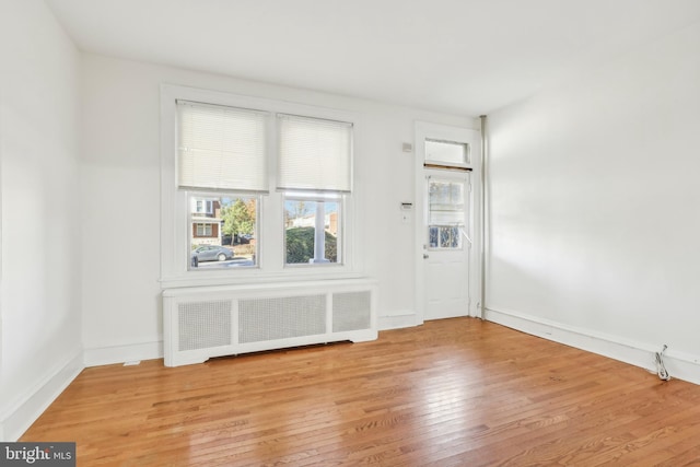 empty room featuring radiator heating unit and light hardwood / wood-style floors